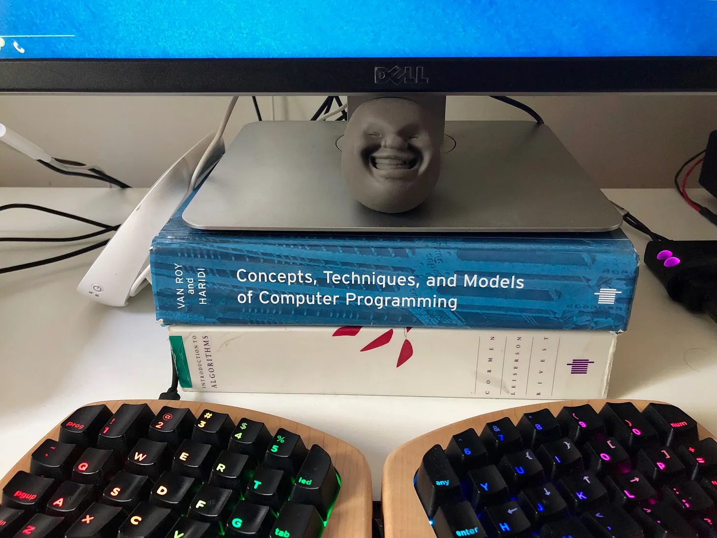 A computer monitor placed on top of old software development books to raise it higher